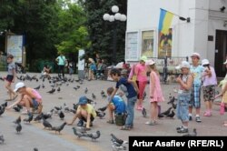 Школьники кормят голубей на площади в Мариуполе