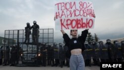 Девушка с плакатом "Твои 80 процентов нарисованы кровью" на фоне приготовившихся избить ее милиционеров во время акции протеста против результатов президентских выборов в Беларуси. Минск, 30 августа 2020 года